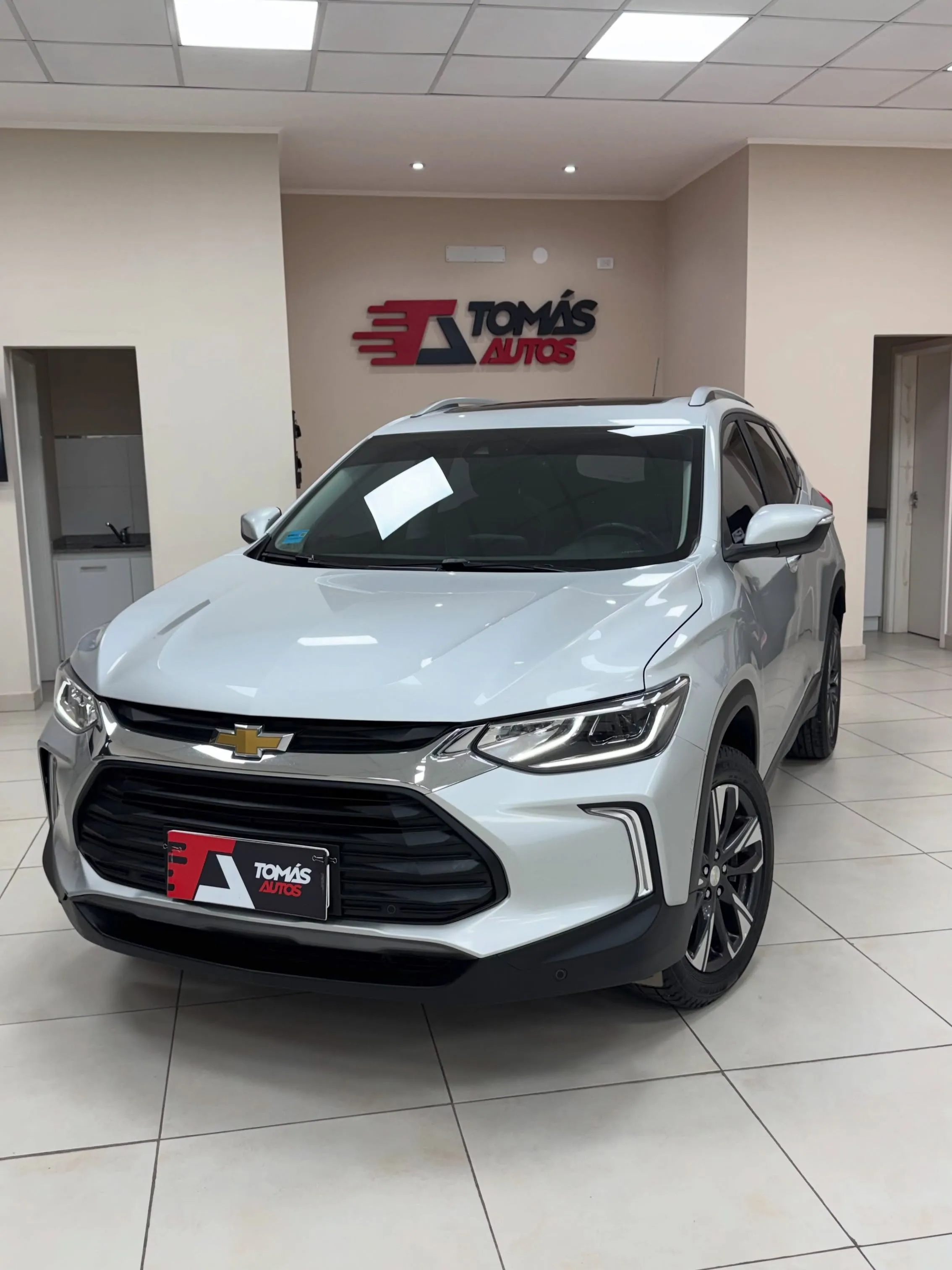 Chevrolet Tracker Premier 2022 blanca, de frente y perfil derecho, bajo el cartel de Tomás Autos
