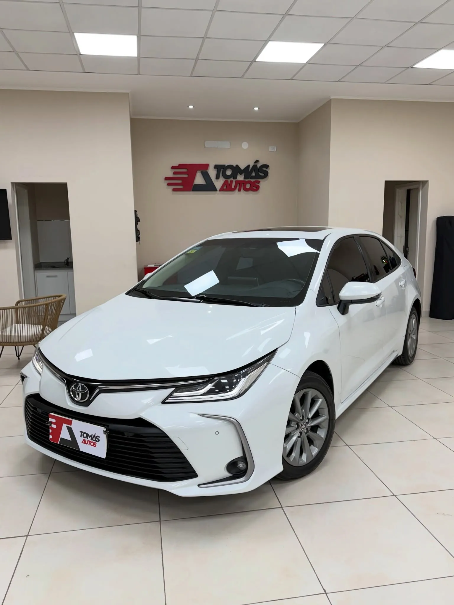 Toyota Corolla XEI 2021 blanco, de frente y perfil izquierdo, en el showroom de Tomás Autos